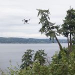 A drone flies above the tree canopy