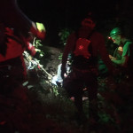 The team readies the attendants. Night time photo of harnessed people ready to go over a cliff.